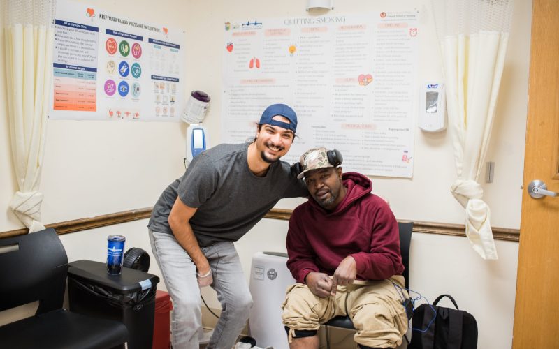 Guest receiving foot care in the clinic sits next to an employee, smiling.