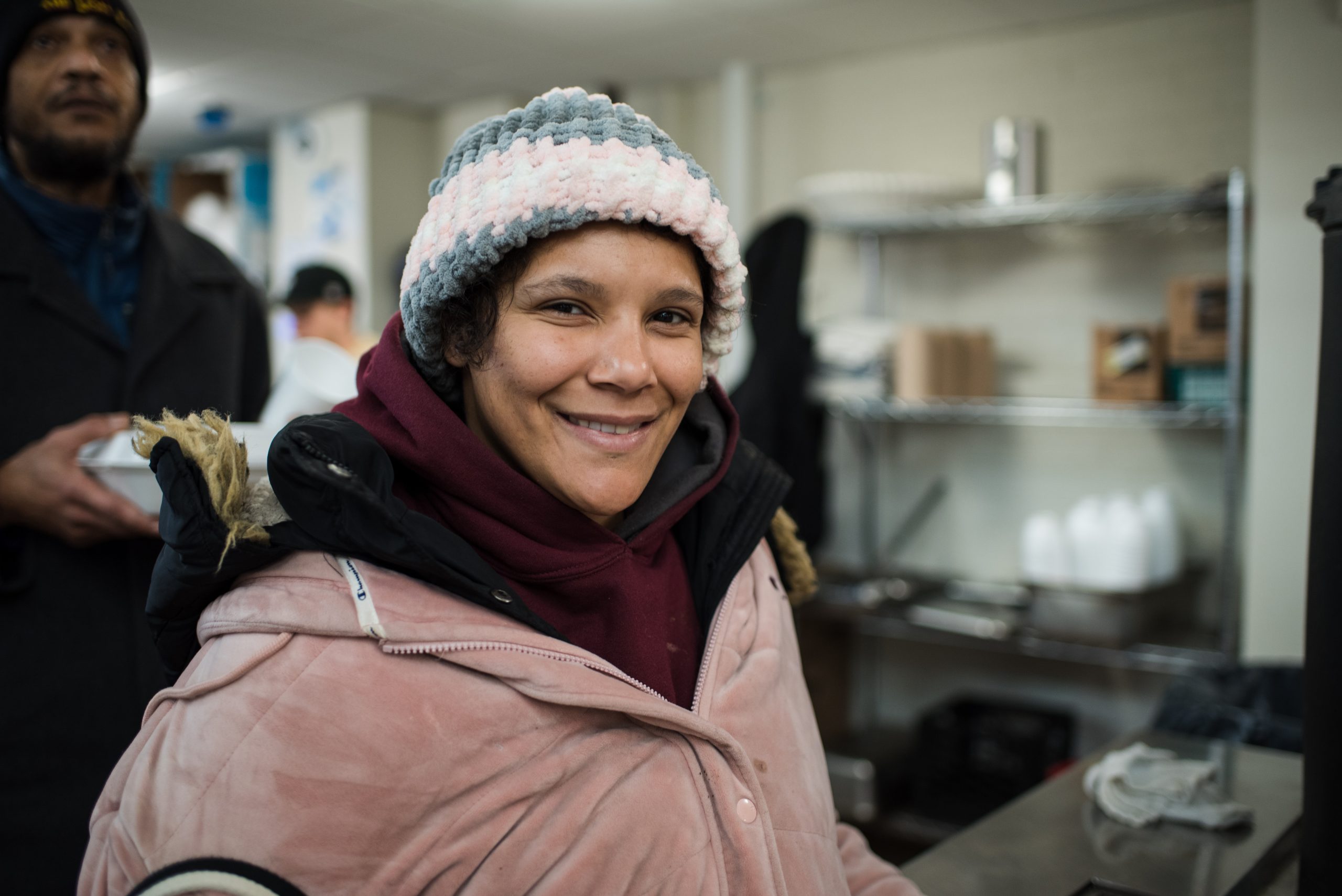 A female guest in winter clothing smiles after being served lunch.